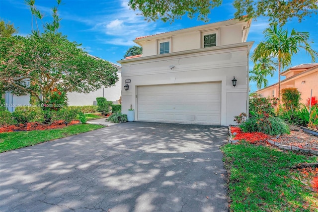 view of front facade featuring an attached garage, aphalt driveway, and stucco siding