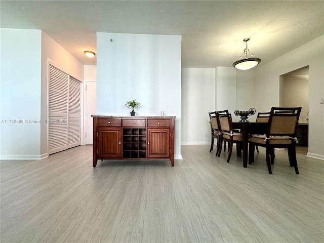 dining area with light wood-type flooring and baseboards