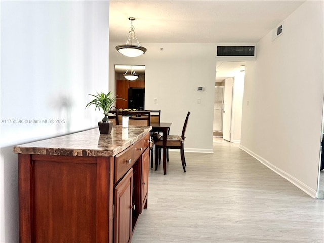 kitchen with light wood-style flooring, visible vents, pendant lighting, and baseboards