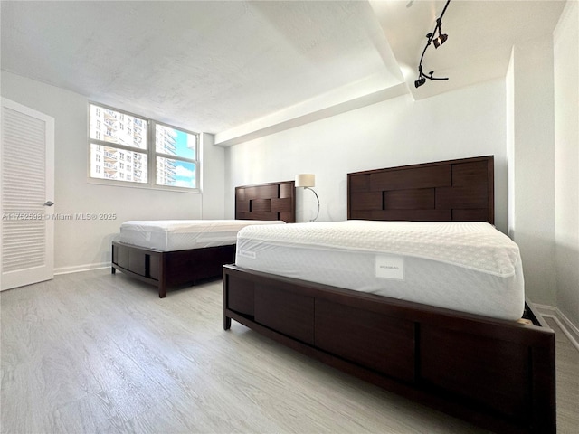 bedroom with light wood-style flooring, baseboards, and track lighting