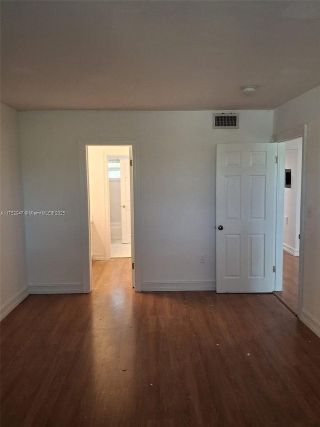 spare room with visible vents, dark wood finished floors, and baseboards