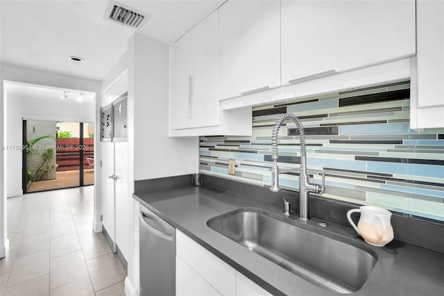 kitchen featuring visible vents, white cabinets, dark countertops, a sink, and stainless steel dishwasher