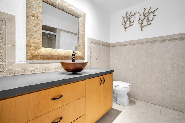 full bath with a stall shower, toilet, tile patterned flooring, vanity, and tile walls