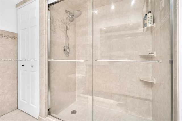 full bath featuring tile patterned flooring, a shower stall, and tile walls