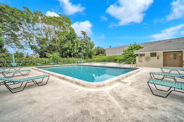 community pool with a patio area and fence