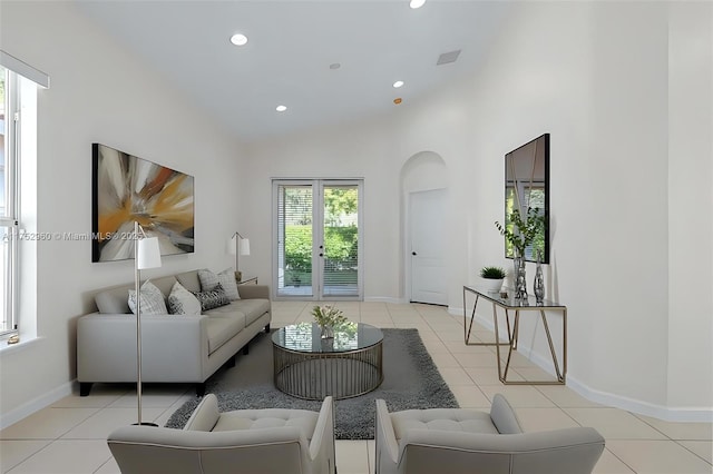 living area featuring light tile patterned floors, high vaulted ceiling, arched walkways, recessed lighting, and baseboards