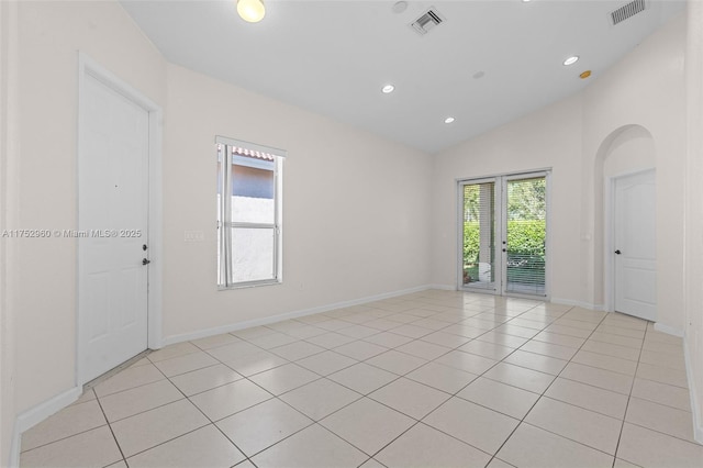 empty room with lofted ceiling, visible vents, and light tile patterned floors