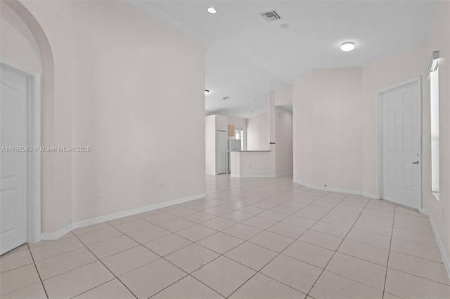 spare room featuring light tile patterned floors, arched walkways, visible vents, and baseboards