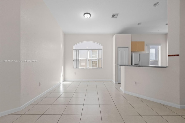 empty room featuring light tile patterned floors, baseboards, and visible vents