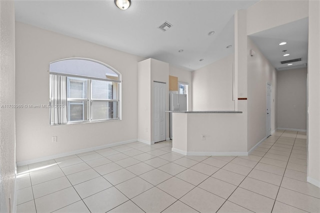 unfurnished room with plenty of natural light, light tile patterned flooring, visible vents, and baseboards