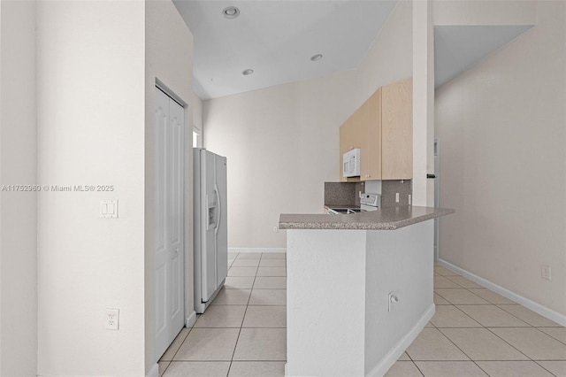 kitchen with white appliances, light tile patterned floors, baseboards, a peninsula, and light brown cabinets