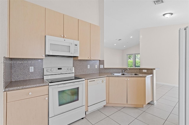 kitchen featuring white appliances, a peninsula, light brown cabinetry, a sink, and light tile patterned flooring