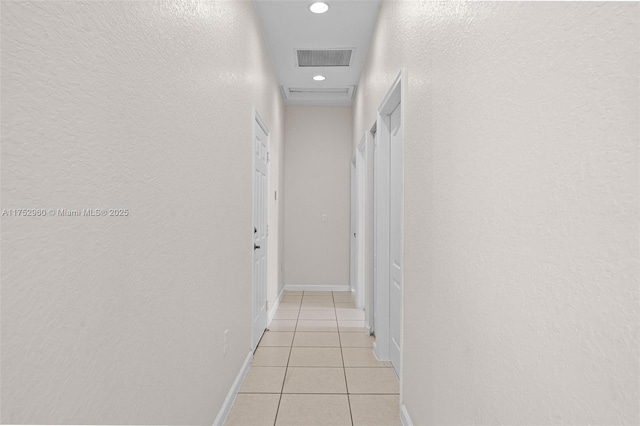 hall featuring light tile patterned floors, baseboards, visible vents, a textured wall, and recessed lighting