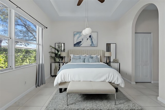 bedroom with baseboards, a raised ceiling, and light tile patterned flooring