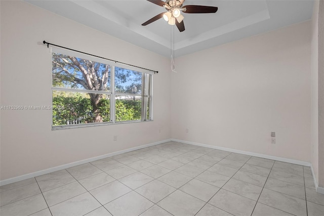 unfurnished room featuring a ceiling fan, a raised ceiling, and baseboards