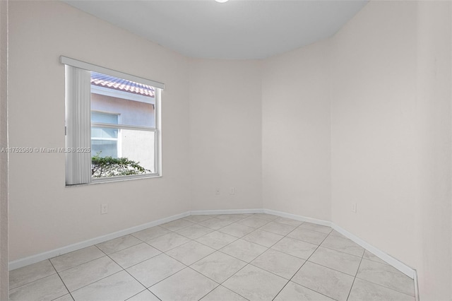 spare room featuring light tile patterned floors and baseboards