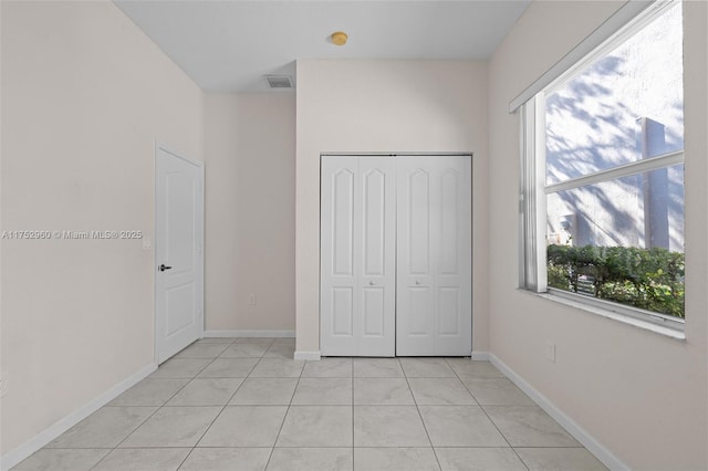 unfurnished bedroom with a closet, multiple windows, visible vents, and light tile patterned floors