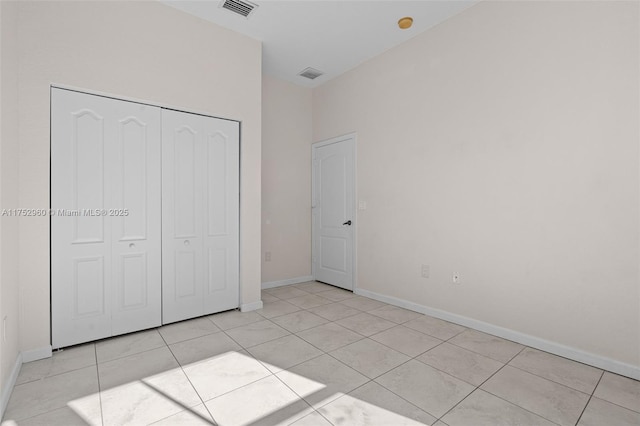 unfurnished bedroom featuring a closet, visible vents, baseboards, and light tile patterned floors