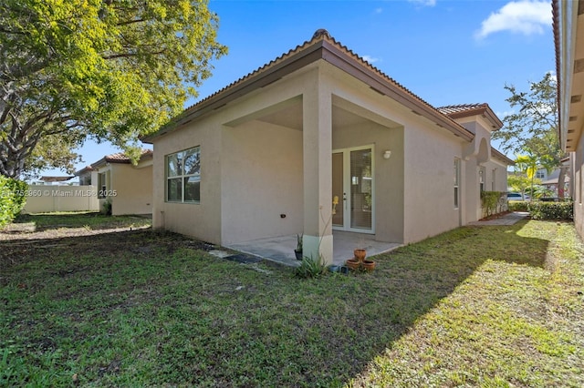 view of home's exterior with a patio area, a lawn, a tiled roof, and stucco siding