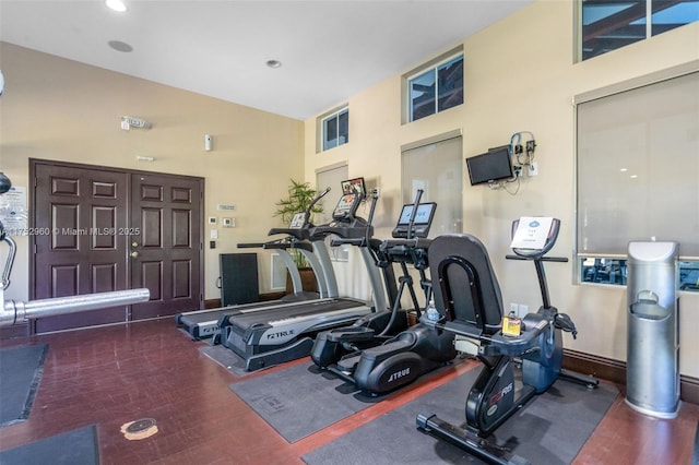 exercise room with a towering ceiling and baseboards