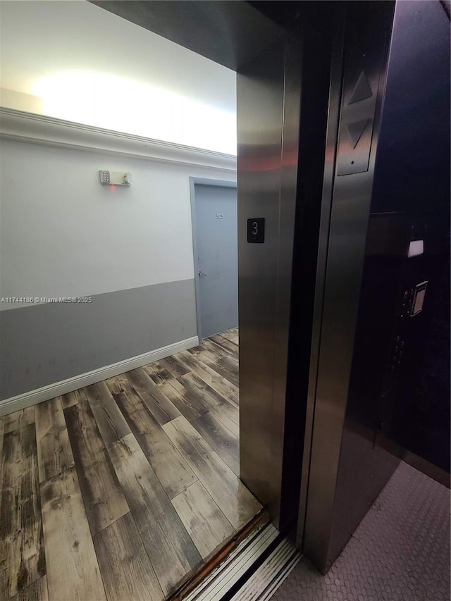 details featuring elevator, baseboards, and wood finished floors