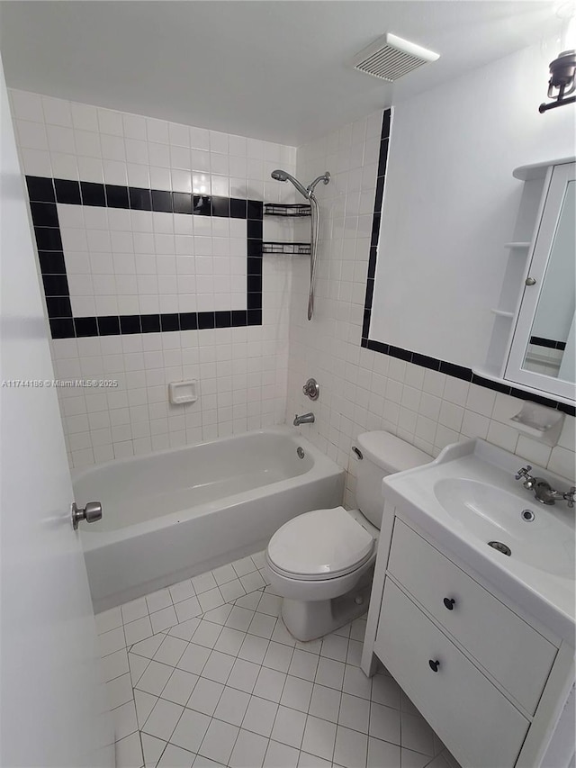 bathroom with toilet, tile patterned flooring, bathtub / shower combination, vanity, and tile walls