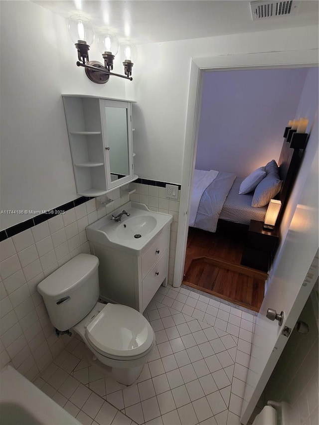 ensuite bathroom featuring toilet, tile walls, visible vents, tile patterned floors, and ensuite bath