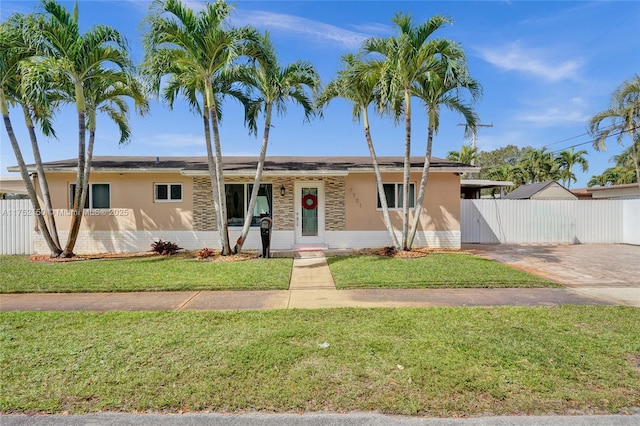 ranch-style home featuring a front yard, fence, and stucco siding