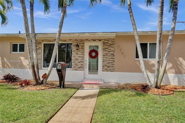 view of front of house featuring a front yard, brick siding, and stucco siding