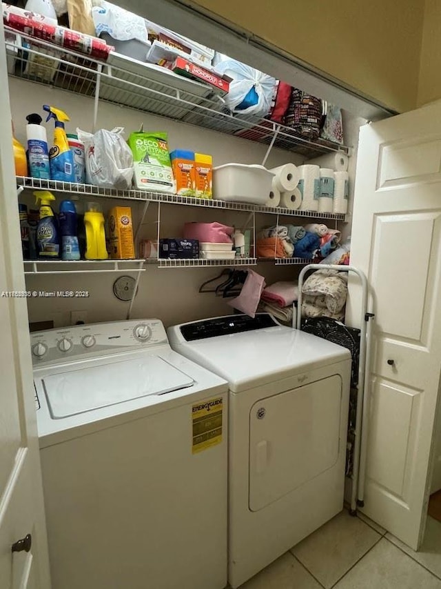 clothes washing area with laundry area, washing machine and dryer, and light tile patterned flooring