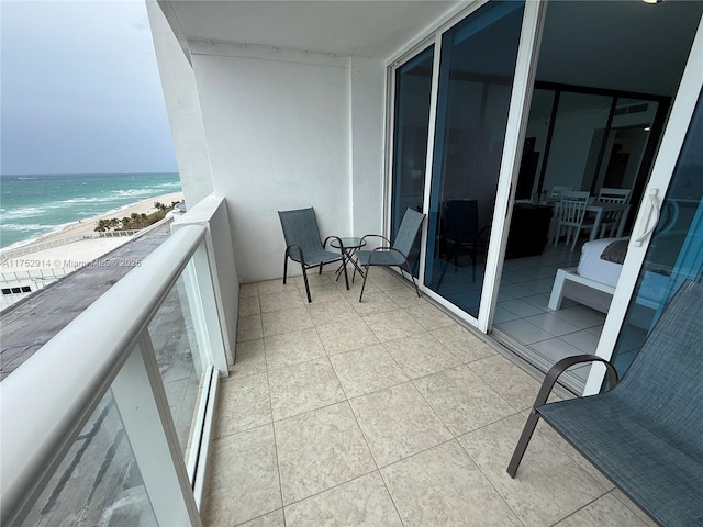 balcony with a water view and a view of the beach