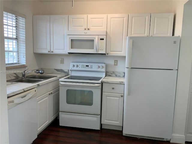 kitchen with dark wood-type flooring, white cabinets, a sink, light stone countertops, and white appliances