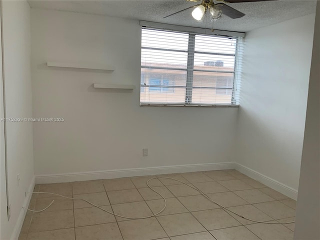 spare room featuring a ceiling fan, a textured ceiling, and baseboards