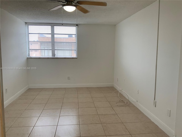 spare room featuring a textured ceiling, ceiling fan, light tile patterned floors, and baseboards