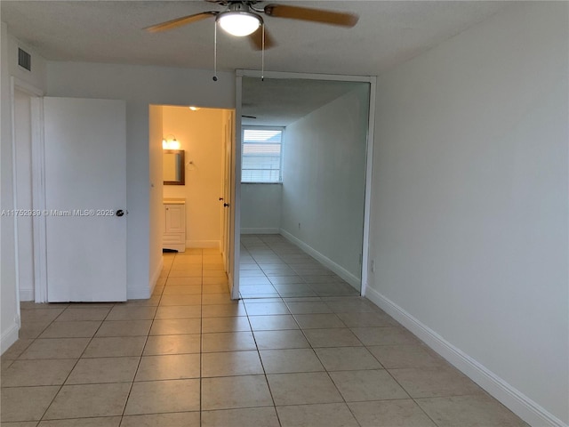 unfurnished room with a ceiling fan, visible vents, baseboards, and light tile patterned floors