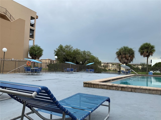 pool with a patio area and fence