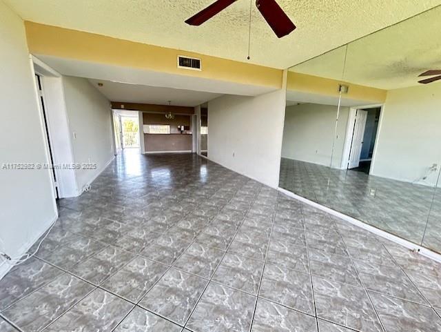 spare room featuring ceiling fan, visible vents, and a textured ceiling