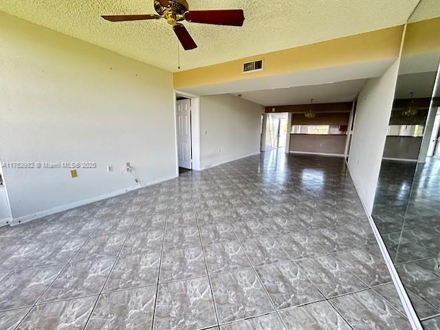 unfurnished living room with a textured ceiling, visible vents, and a ceiling fan