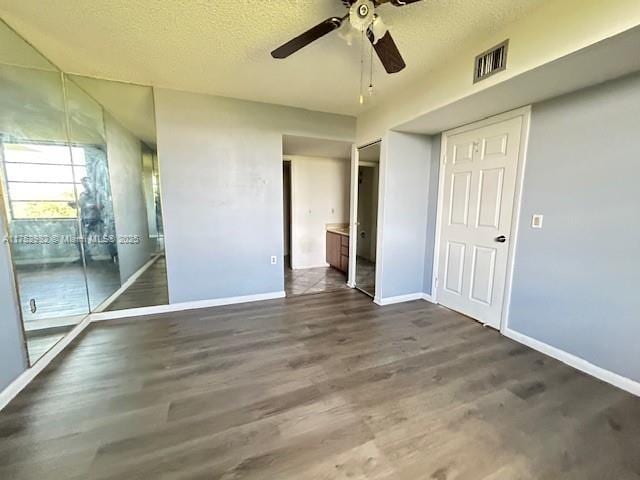 unfurnished bedroom with dark wood-style flooring, visible vents, and a textured ceiling