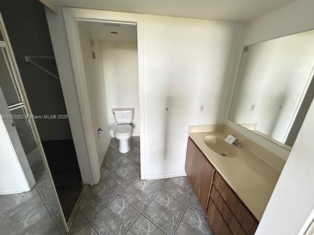 bathroom with toilet, vanity, and baseboards