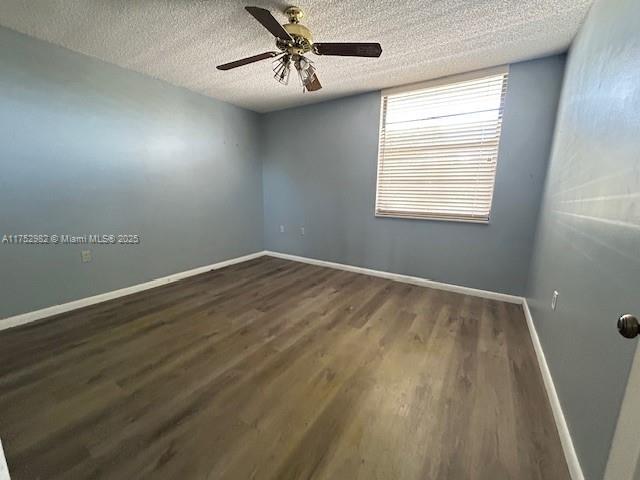 spare room with ceiling fan, baseboards, dark wood-style flooring, and a textured ceiling