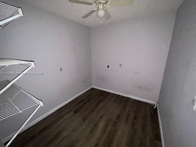 spare room with ceiling fan, a textured ceiling, baseboards, and dark wood-type flooring