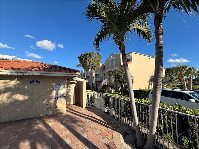 view of property exterior with a tile roof, a residential view, fence, and stucco siding