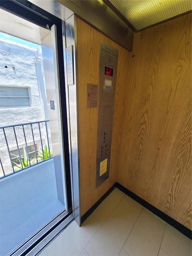 interior space featuring wood walls, light tile patterned flooring, and elevator