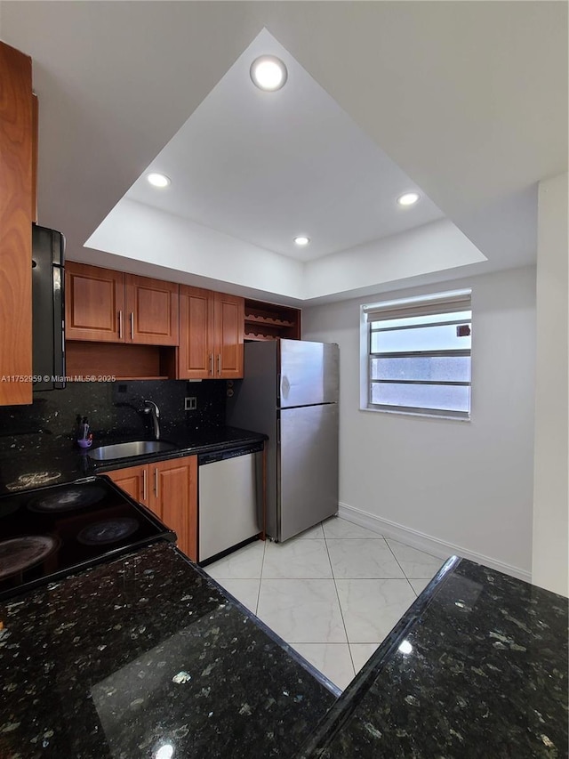 kitchen featuring a raised ceiling, brown cabinets, stainless steel appliances, open shelves, and a sink