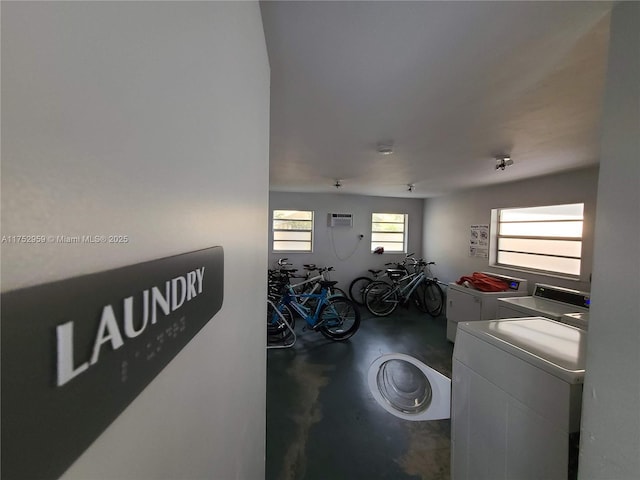 laundry area with an AC wall unit, washing machine and clothes dryer, and laundry area