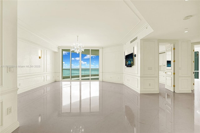 empty room featuring crown molding, expansive windows, a notable chandelier, and a decorative wall