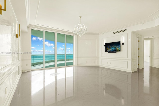 empty room featuring floor to ceiling windows, a notable chandelier, visible vents, a decorative wall, and ornamental molding