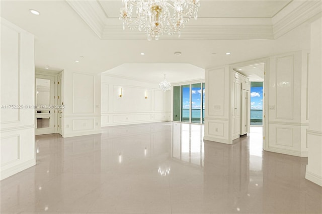 spare room with marble finish floor, a tray ceiling, crown molding, a chandelier, and a decorative wall