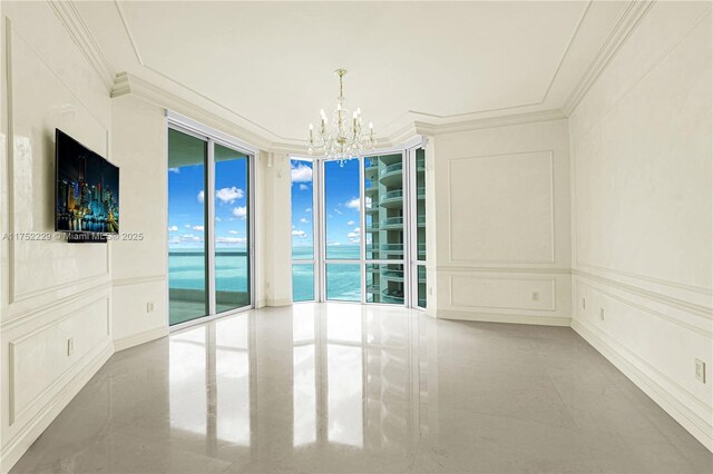 unfurnished room with crown molding, floor to ceiling windows, a notable chandelier, and a decorative wall